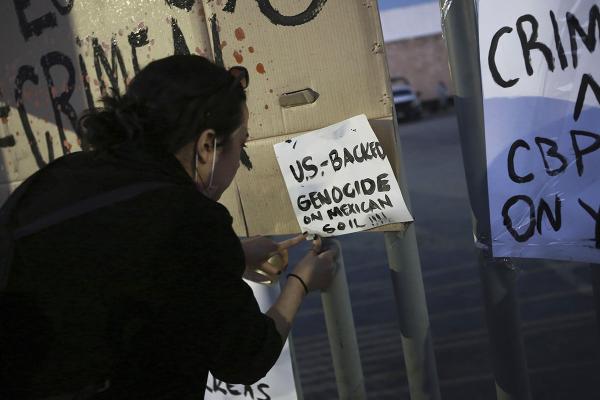 Ciudad Juarez, activist protests with sign that says: "U.S. backs genocide on Mexican soil!"