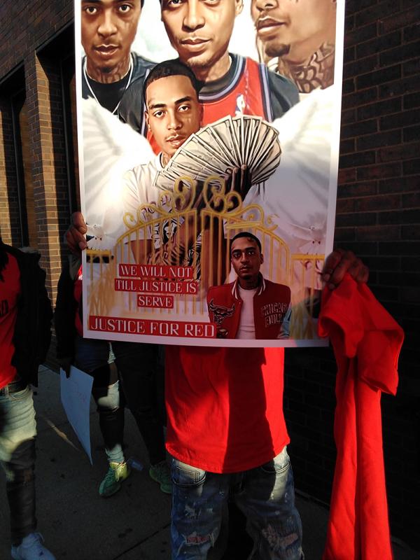 Members at vigil for Lil Red, hold a poster honoring him.