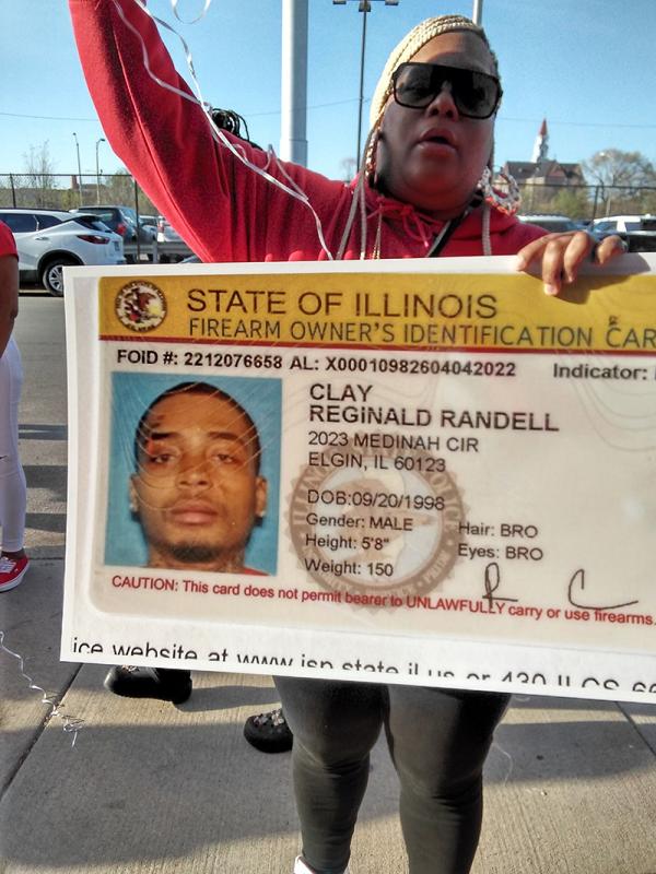 Mourner holds enlargement of Reginald Clay's ID.