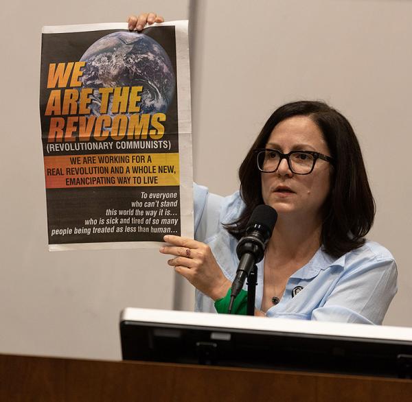 Sunsara Taylor holds up broadsheet WE ARE THE REVCOMS at "Woke Lunacy vs Real Revolution" talk at UCLA, May 25, 2023.