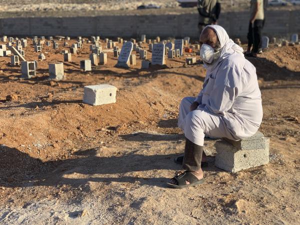 A grieving man next to a field of graves