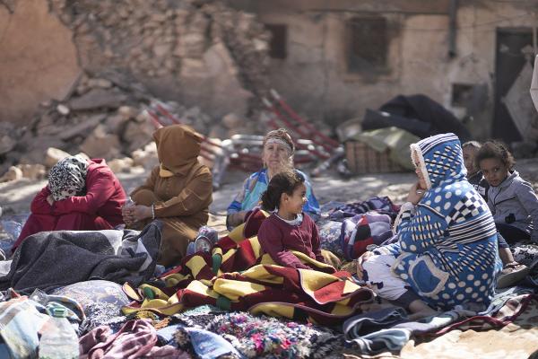 Villagers from Moulay Brahim near Marrakech, Morocco, on a blanket amidst devastation.