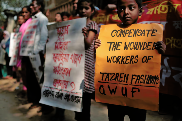 Relatives of victims of the Tazreen factory fire demonstrate, November 24, 2014. The center sign reads, “Sumaya Khatun, a victim of Tazreen Fashions fire—where is compensation?”