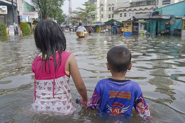 Children wade through floodwaters in Bandung, West Java, Indonesia