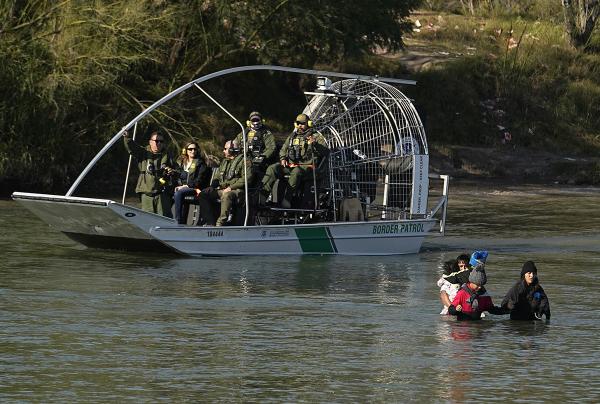 Migrants crossing the Rio Grande at Eagle Pass, Texas, are watched by border patrol agents, January 3, 2024.