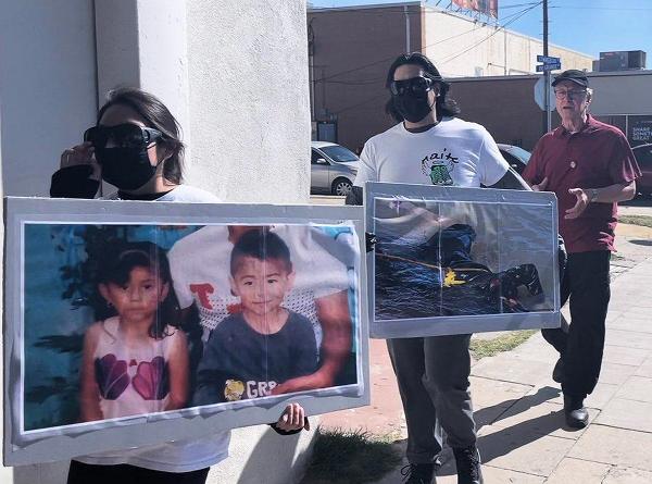 RevComs with signs of immigrant children who drowned at Eagle Pass, Texas.