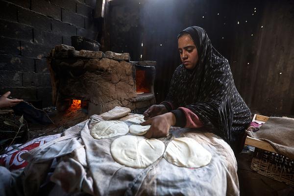 Palestinian woman displaced from Gaza Strip bakes bread at tent camp in Rafah, February 23, 2024.