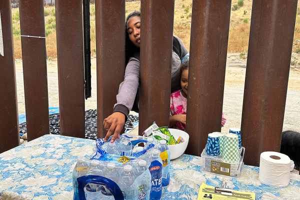 A woman seeking asylum reaches for a bottle of water after crossing the border with a child, June 5, 2024, in San Diego.