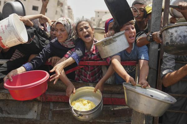 Palestinians struggle to get food at a community kitchen in Gaza City, August 16, 2025.