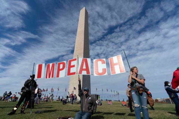 At Trump Must Go Now rally, protesters hold up letters spelling IMPEACH.