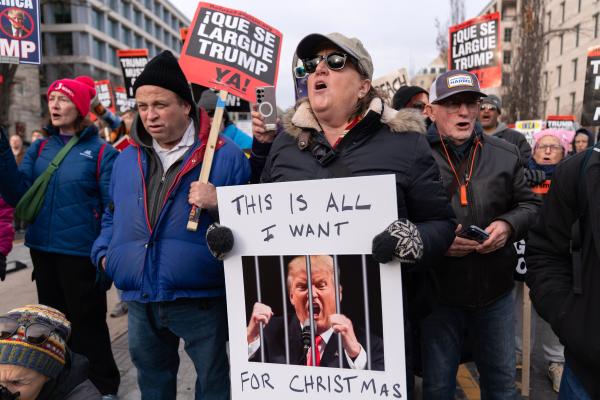 Man with sign All I Want For Christmas (Trump behind bars), December 13, 2025.