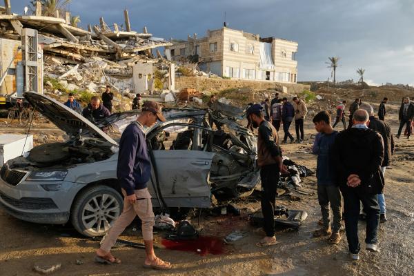 Palestinians look at a car destroyed by an Israeli strike in Gaza City, December 13, 2025.