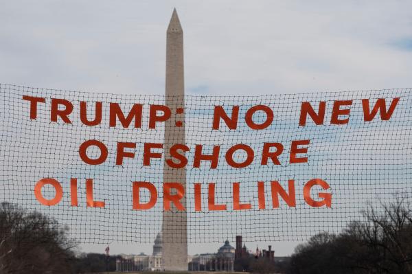 Activists in hazmat suits hold banner in front of the Lincoln Memorial Reflecting Pool, January 22, 2026.