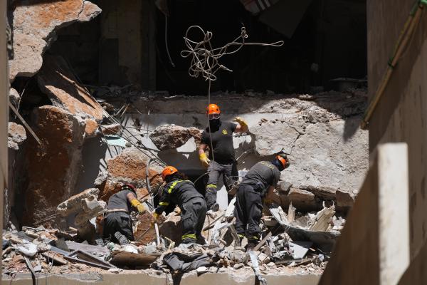  Lebanese workers search through rubble from Israeli airstrike for the body of missing student, April 11, 2026.