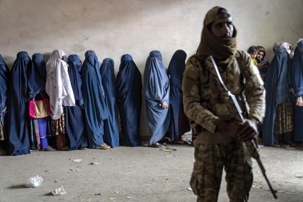 A Taliban fighter stands guard as women wait for food rations from a humanitarian aid group in Kabul, Afghanistan, May 23, 2023.
