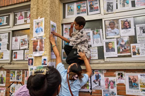 A young boy posts photographs of missing relatives on a wall outside a hospital in Kathmandu, Nepal, August 30, 2026.