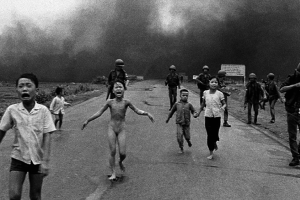 People severely burned from napalm attack run down the road.