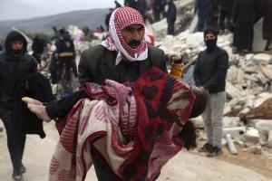 Man carries body of victim of 7.8 earthquake near border of Syria and Turkey, February 6, 2023.