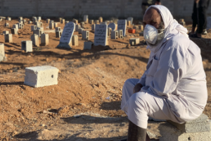 A grieving man sits by graves of flash flood victims in Derna, Libya, Friday, Sept. 15, 2023.