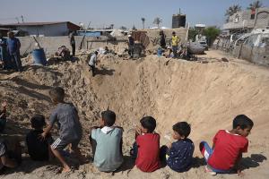Children gather around a huge crater in refugee camp in Khan Younis from Israeli airstrike, June 21, 2024.