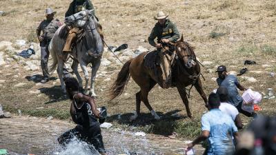 Mounted Texas Border Patrol on horseback whip and yell at Haitian immigrants who crossed the Rio Grande River from Mexico into the U.S. 