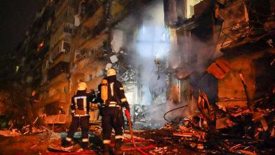 Firemen in front of burning building in Kyiv, Ukraine destroyed by Russian fire attack