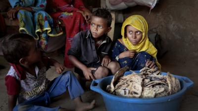 Children sit around moldy bread at shelter in Yemen.