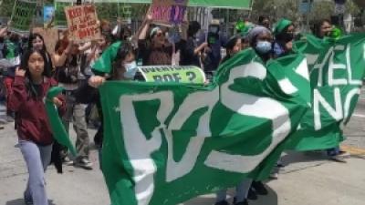 Young woman marching behind green banner