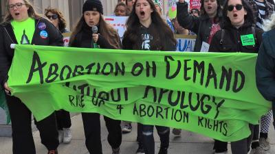 Lansing, Michigan, women march with banner, "Abortion on Demand Without Apology,", October 8, 2022