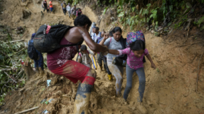 Venezuelan migrants wade through mud to cross the Darién Gap.