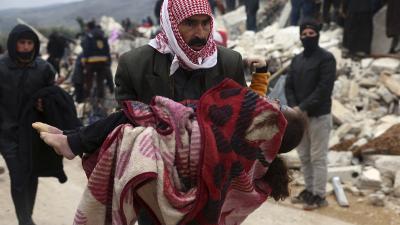 Man carries body of victim of 7.8 earthquake near border of Syria and Turkey, February 6, 2023.