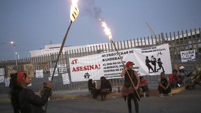 Mexico, Ciudad Juarez, protest fire that killed 39 migrants with signs on fence and torches, March 29, 2023.