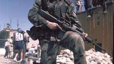 U.S. Marine kneels on back of Haitian during 1994 invasion of Haiti.