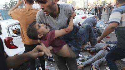 Palestinian carries a boy injured from Israeli airstrike outside the entrance of the al-Shifa hospital in Gaza City, November 3, 2023.