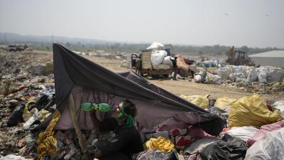  At a garbage dump on the outskirts of Jammu, India, June 19, 2024, man drinks water in the shade of trash.