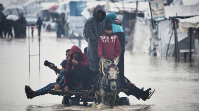 Palestinians cross area flooded by storm Byron in Khan Younis, December 11, 2025
