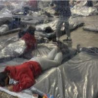 Immigrants in detention under mylar blankets