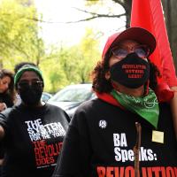 Women carrying red flags listen to speakers at New York City May Day rally.