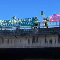 Holding banner Legal Abortion Nationwide Now on overpass