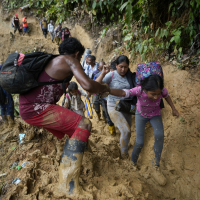 Venezuelan migrants wade through mud to cross the Darién Gap.
