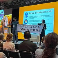 Chicago_Peter Kalmus and Rose Abramoff unfurl a banner that says "Out of the Labs and Into the Streets" during a plenary at the American Geophysical Union.