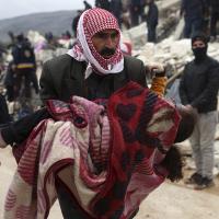 Man carries body of victim of 7.8 earthquake near border of Syria and Turkey, February 6, 2023.