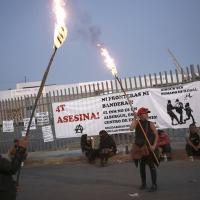 Mexico, Ciudad Juarez, protest fire that killed 39 migrants with signs on fence and torches, March 29, 2023.