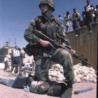 U.S. Marine kneels on back of Haitian during 1994 invasion of Haiti.