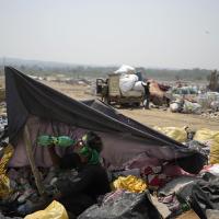  At a garbage dump on the outskirts of Jammu, India, June 19, 2024, man drinks water in the shade of trash.