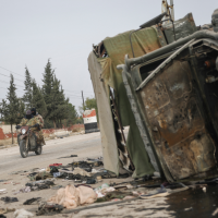 Syrian opposition fighters drive past a damaged government vehicle south of Hama, Syria, on Saturday, December 7, 2024.