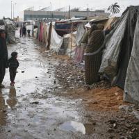  Mother and child examine damage from flooding at a tent camp in the central Gaza Strip, November 14, 2025.