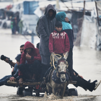 Palestinians cross area flooded by storm Byron in Khan Younis, December 11, 2025