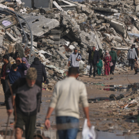 Palestinians walk along a street surrounded by buildings destroyed during Israeli air and ground operations in Gaza City, December 17, 2025.
