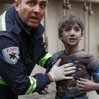 A first responder assists an injured boy following a U.S.-Israeli airstrike on a residential building in Tehran, Iran, March 28, 2026.